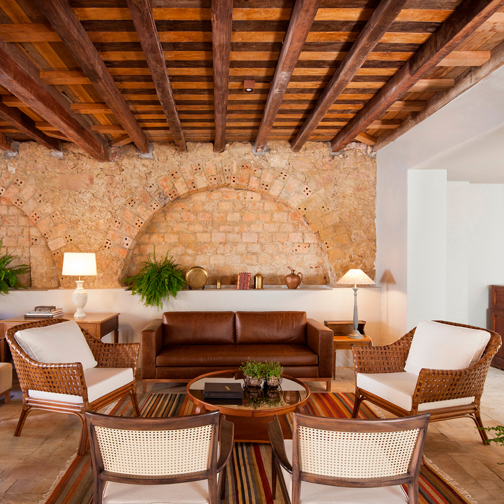 Recepção do hotel villa amazonas. parede de tijolos à mostra com um sofá de couro e algumas cadeiras