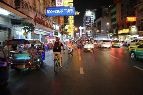 Ruas da cidade de Bankgok a noite. CArros, bicicletas e motos andando juntos.