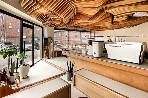 Interior do Perception Cafe, com seu teto ondulado em madeira marron.