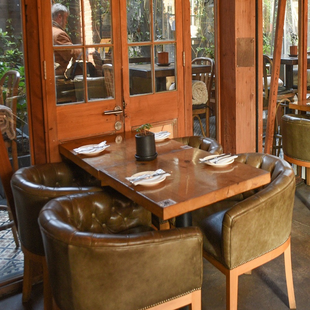 Mesa em madeira com cadeiras em couro, combinadno com a decoração do restaurante do Hotel.