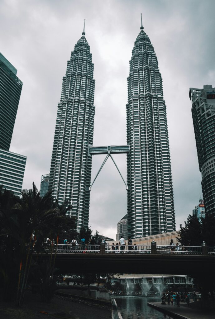 Dois gigantescos edifícios no centro de Kuala Lumpur em formato de torres modernas interligadas por uma ponte. É a Petronas Towers projetadas por Cesar Pelli.