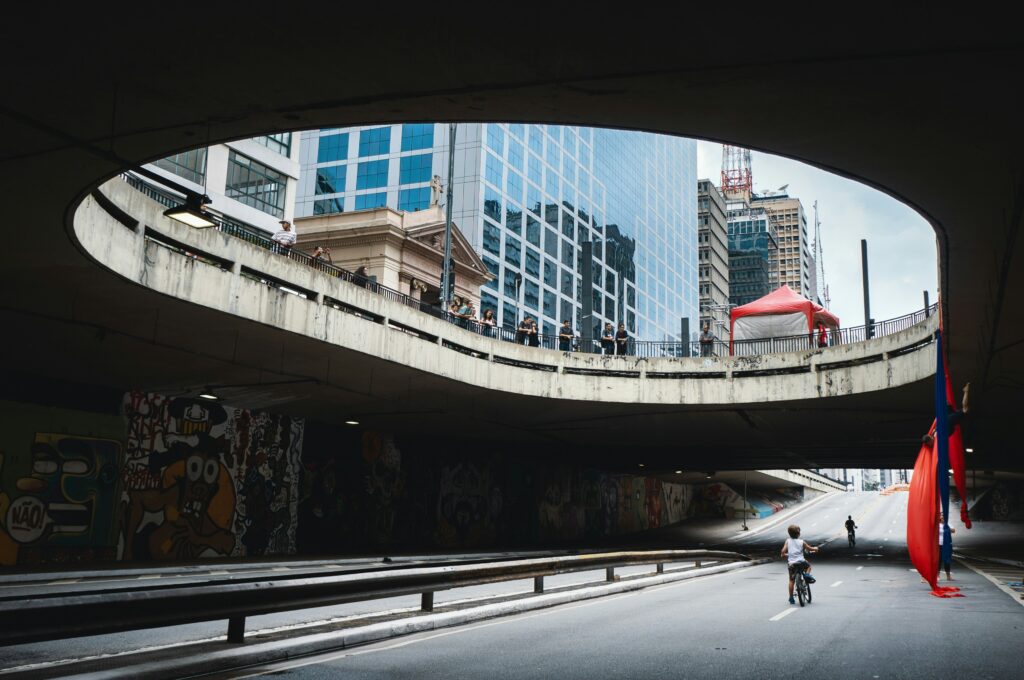 Foto de um viaduto na Avenida Paulista onde se vê pessoas olhando a vista e uma criança de bicicleta. Onde ficar em São Paulo