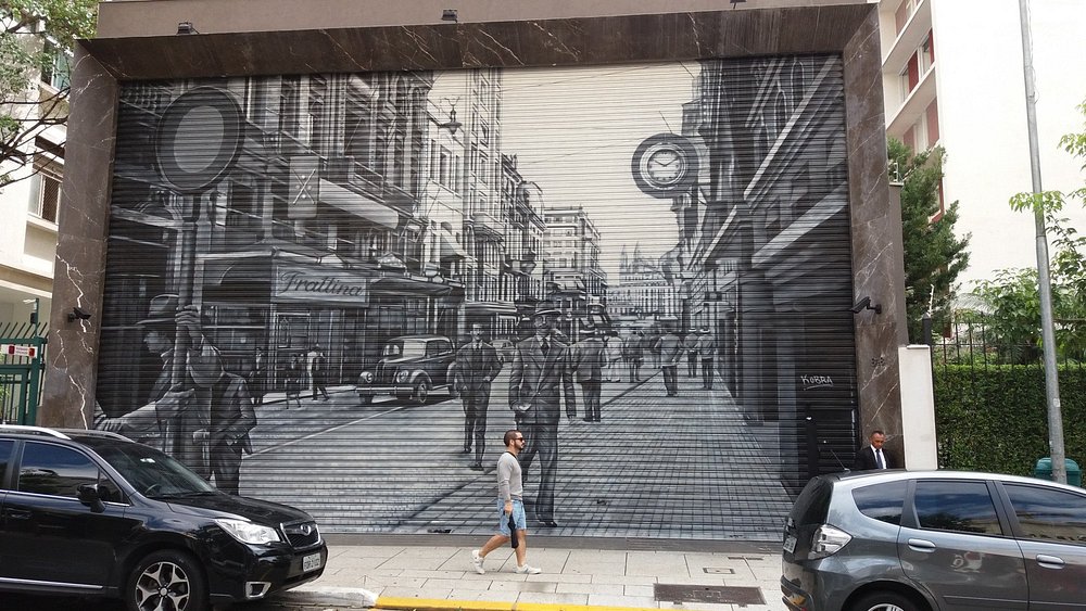 Foto mostra uma arte num portão da rua Oscar Freire e um homem andando, ao centro da foto. Onde ficar em São Paulo.