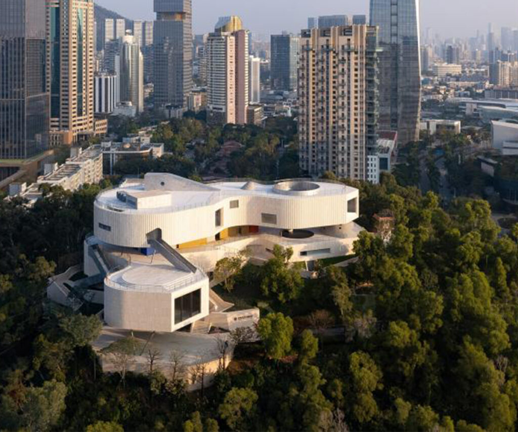 Fachada do Museu China Merchants History em meio a árvores e com  a cidade ao fundo