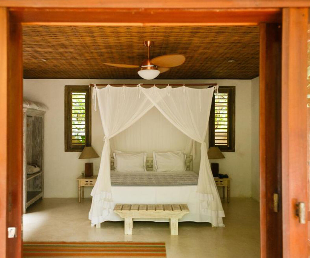 Acomodação da Pousada Capim Santo - quarto com cama, mesas de cabeceira e estante