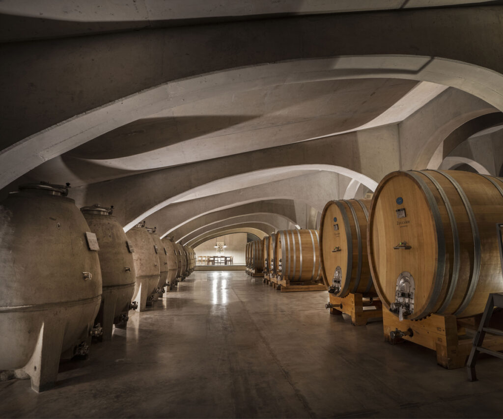 área de armazenamento de vinhos com recipientes de concreto e madeira