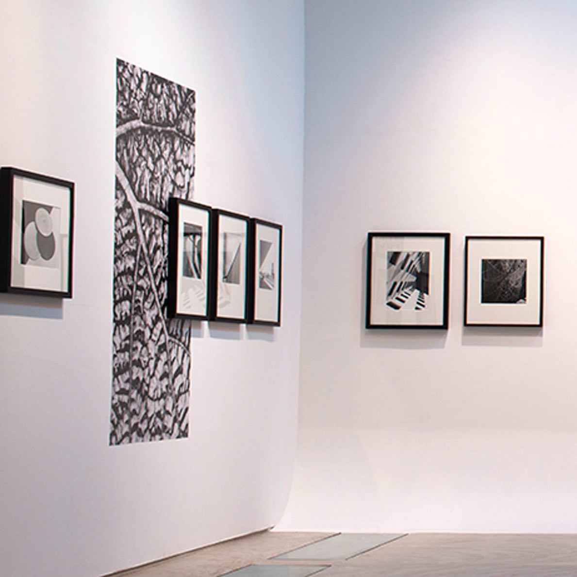 A imagem mostra uma exposição de arte moderna na Galeria da Gávea, no Rio de Janeiro. A exposição é dedicada a Gertrudes Altschul e apresenta várias obras em preto e branco. As paredes brancas e o chão de concreto contribuem para um ambiente minimalista e moderno.