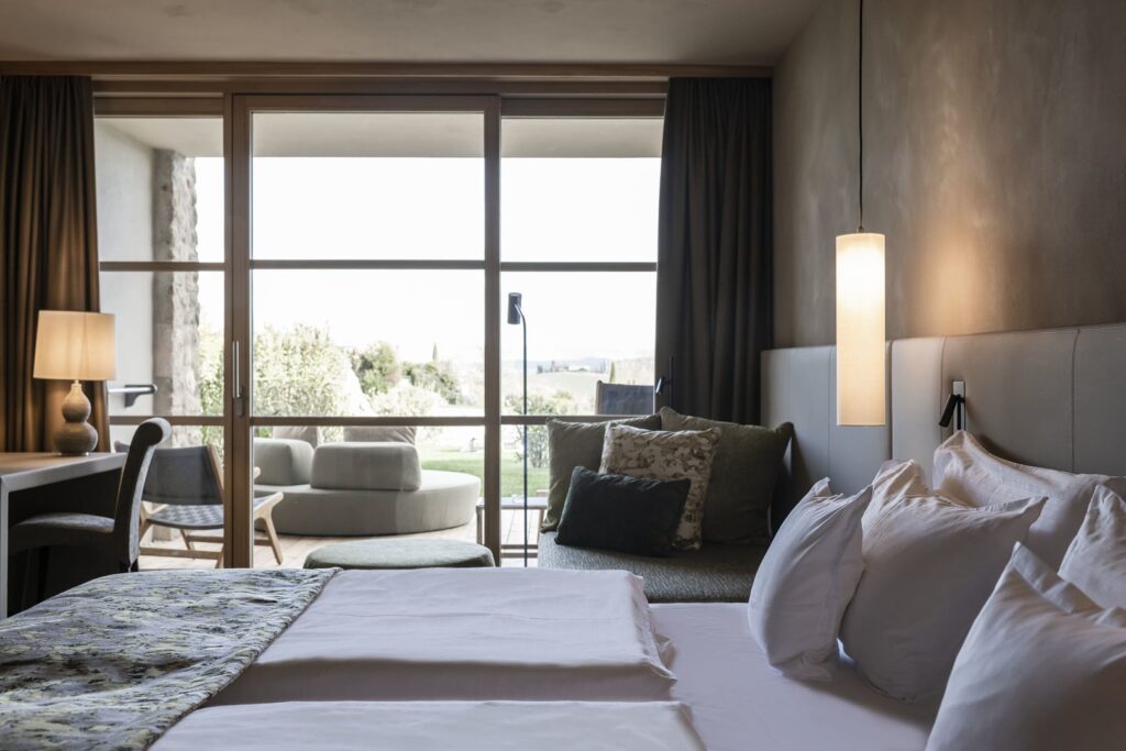 Melhores hotéis na Toscana: quarto moderno no Adler Resort com travertino e vista para jardins