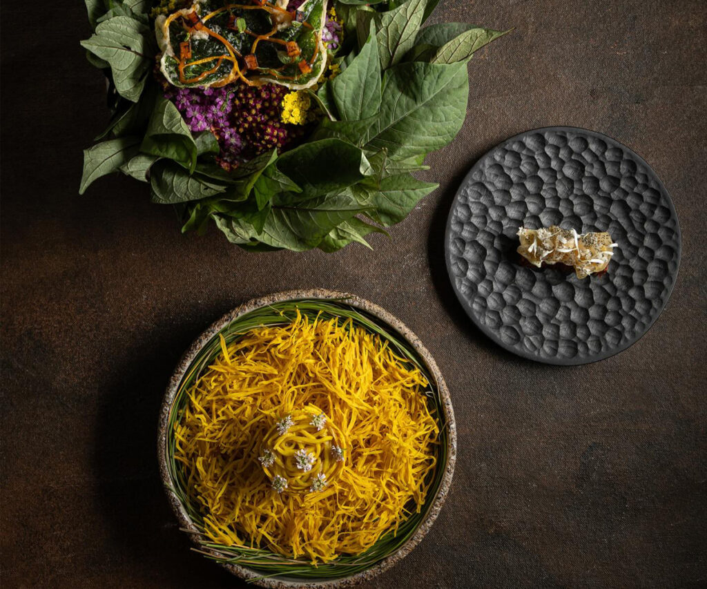Gastronomia peruana com pratos coloridos e decorativos em mesa moderna.