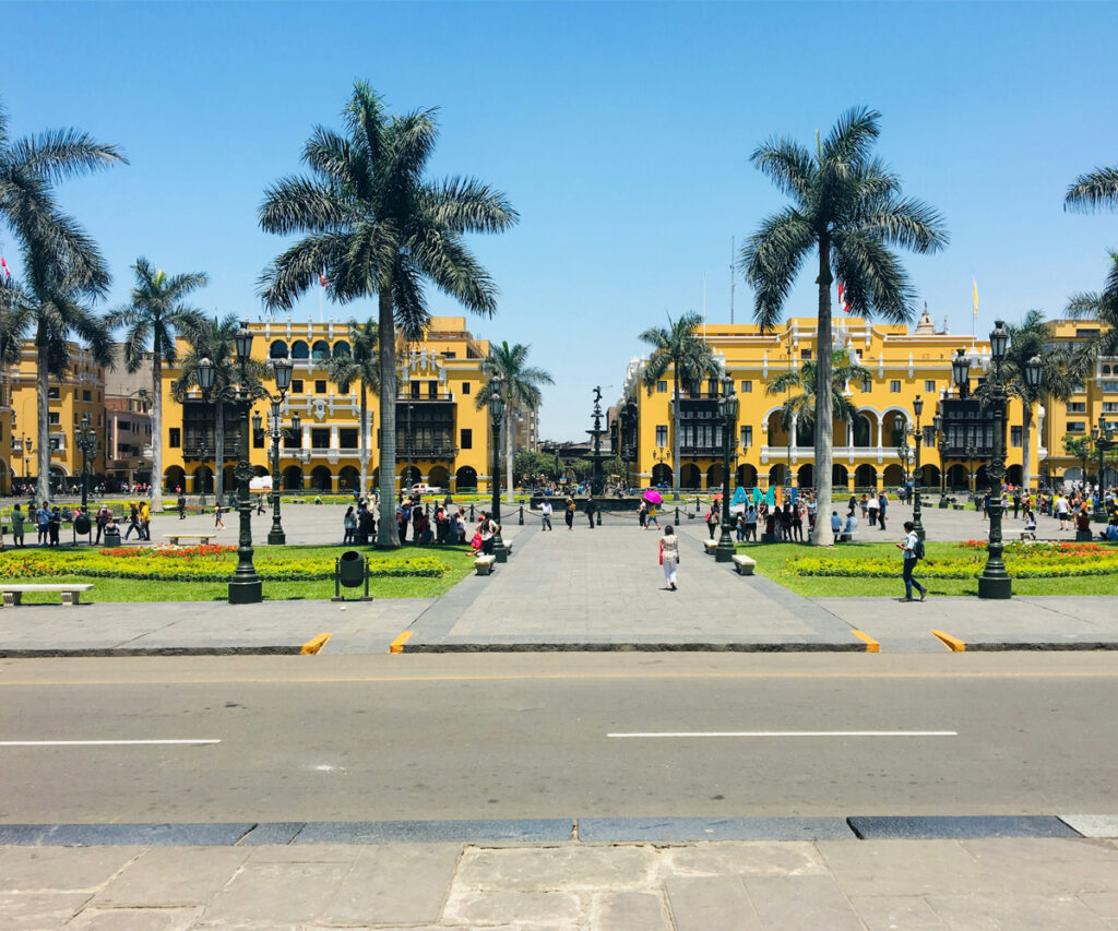 Melhor época para viajar para o Peru: Praça principal em Lima com edifícios amarelos e palmeiras.