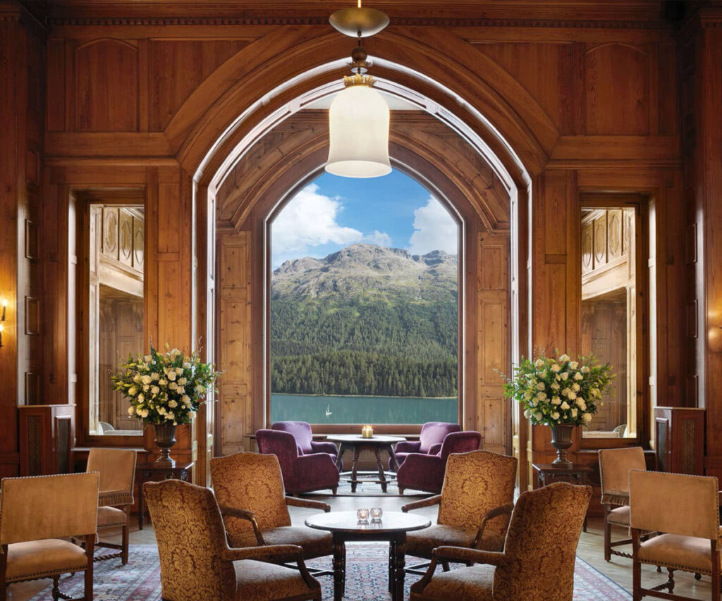 Luxuoso lobby do Badrutt's Palace em St. Moritz com móveis de madeira e vista para montanhas