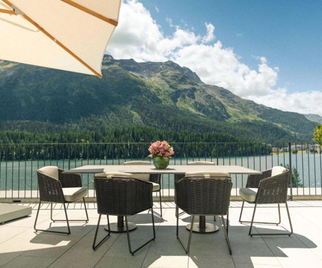 Varanda moderna com vista para montanhas e lago, mesa com flores, St. Moritz