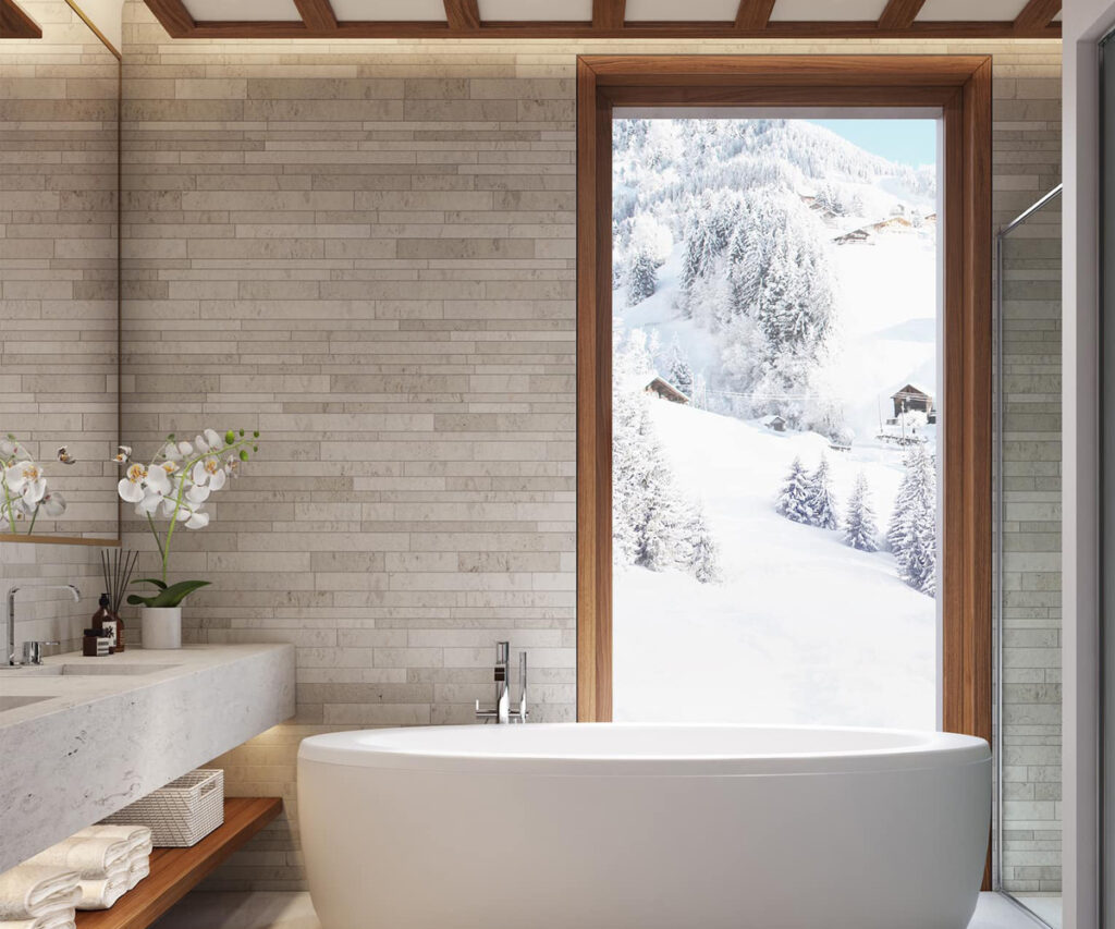 Onde ficar em St Moritz: banheiro moderno com vista para montanhas nevadas e banheira branca.