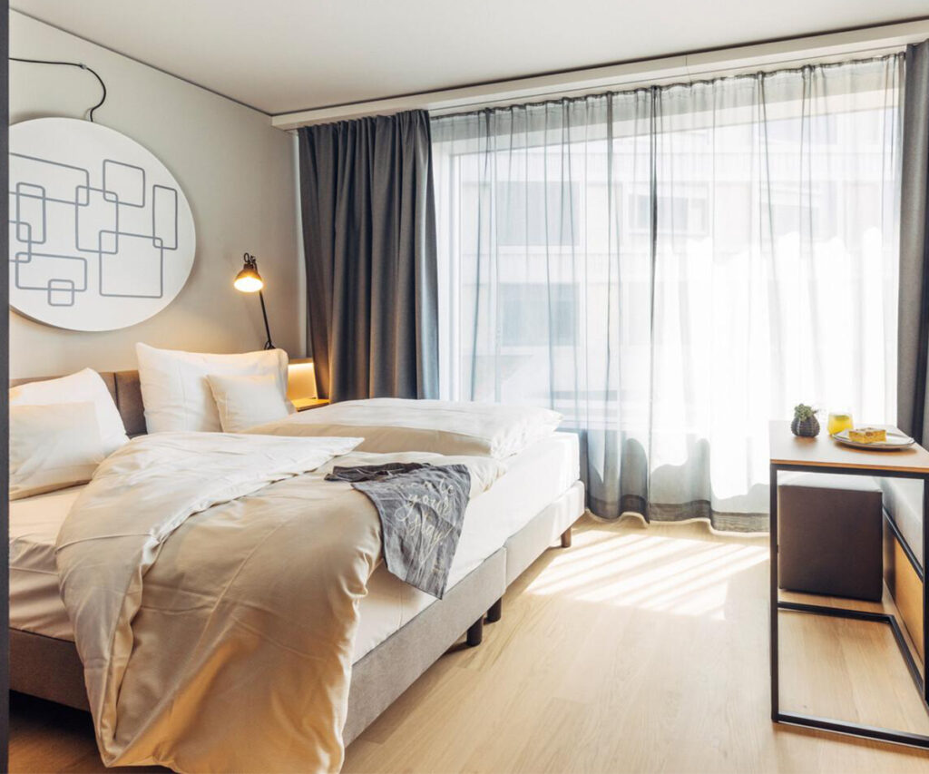 Quarto moderno de hotel com cama arrumada e decoração elegante em Berna