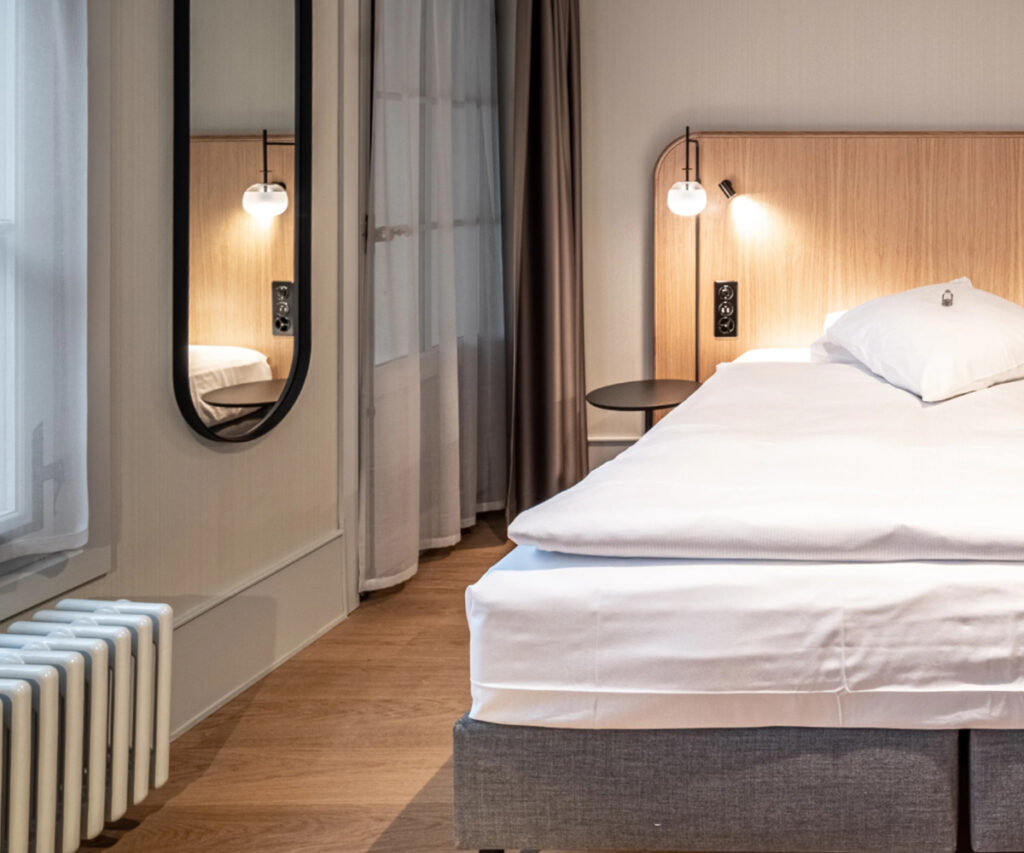 Onde ficar em Berna: quarto moderno com cama branca e iluminação suave.