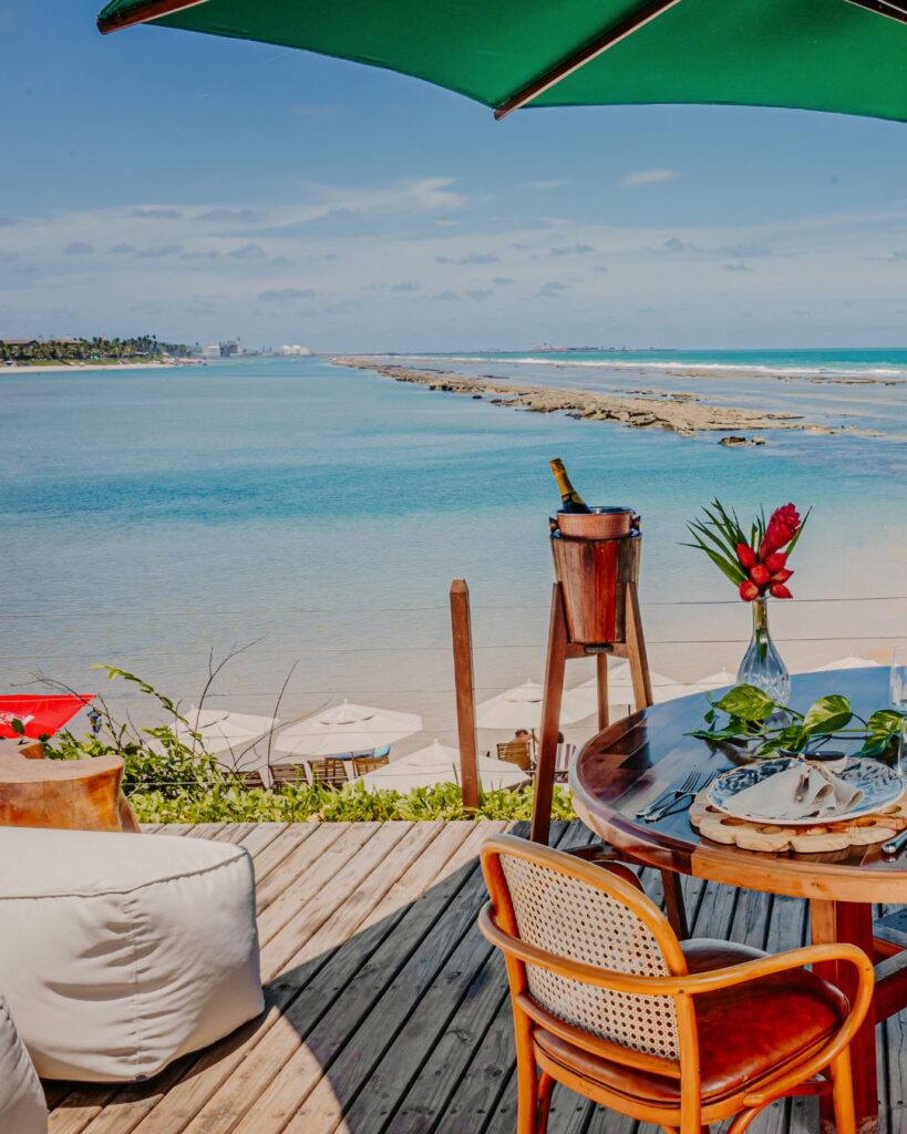 Vista paradisíaca de bangalô no Nannai Muro Alto, Porto de Galinhas, PE, com mesa decorada e praia