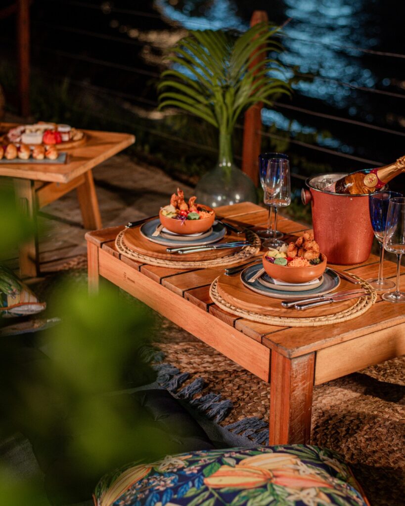 Resorts no nordeste: decoração tropical no Nannai Muro Alto, Porto de Galinhas, PE, com mesa de madeira e alimentos.