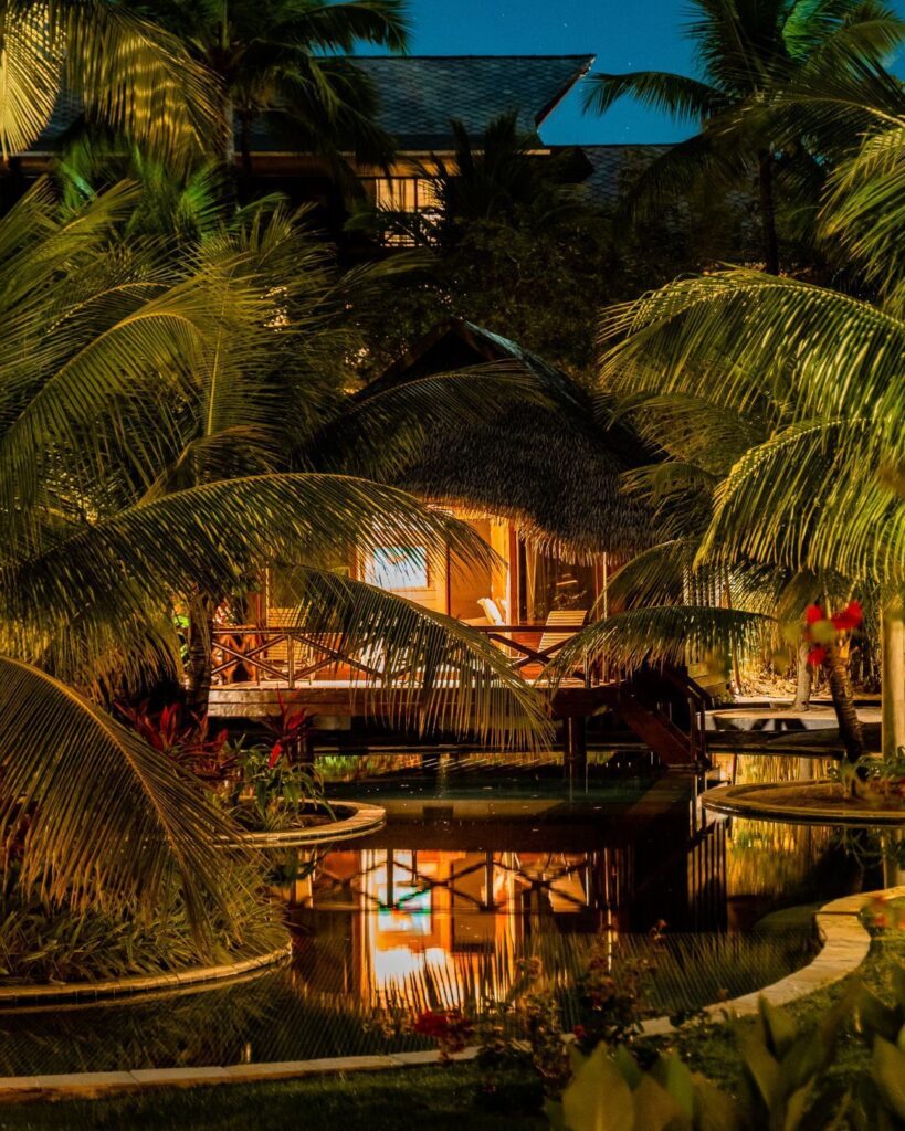 Bangalô tropical no Nannai Muro Alto, Porto de Galinhas, PE, com palmeiras e iluminação noturna