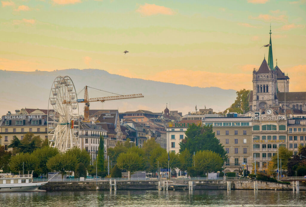 Genebra suiça: paisagem urbana com lago, montanhas e Jet d’Eau iluminado.