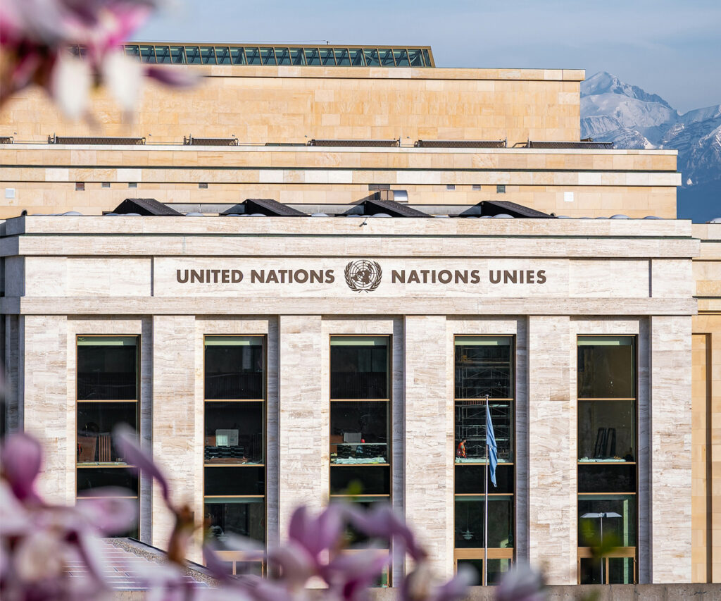 Fachada da sede europeia da ONU em Genebra, Suíça, com montanhas ao fundo