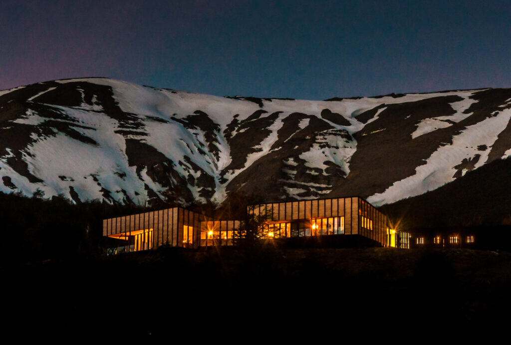 Hospedagem em Torres del Paine à noite com montanhas nevadas ao fundo