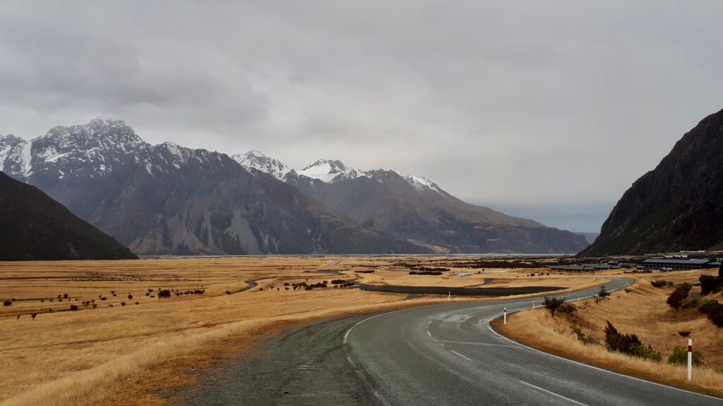 Viagem para Nova Zelândia: paisagem de Mount Cook, montanhas nevadas e estrada sinuosa em parque nacional deslumbrante