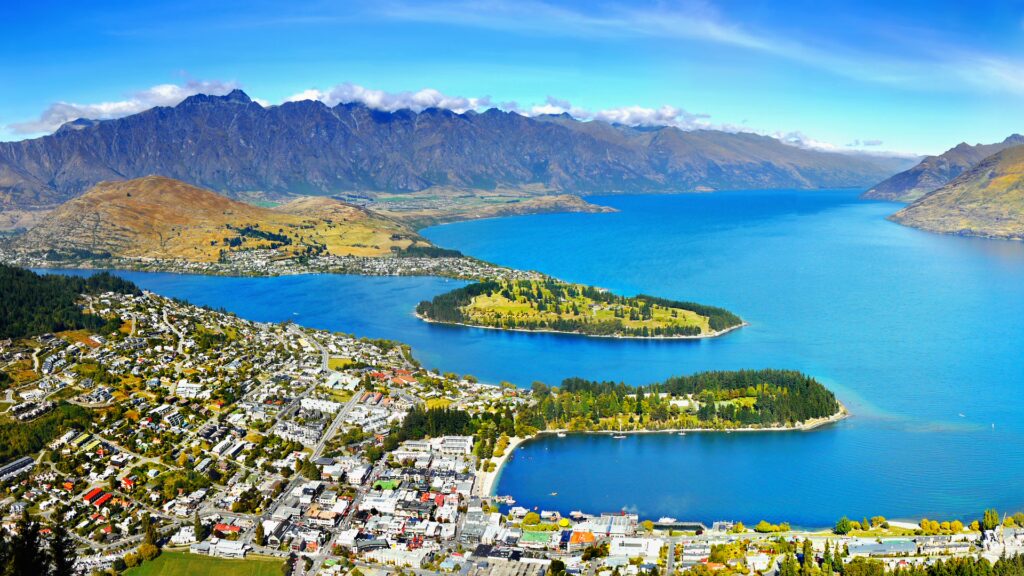 Viagem para Nova Zelândia: paisagem deslumbrante de Queenstown, lago e montanhas com cidade pitoresca à beira d'água