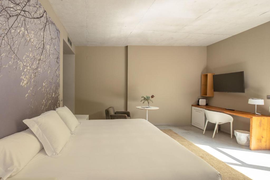 Quarto minimalista do hotel viura com cama clean, mesa de trabalho e TV integrada, elegância moderna e natural