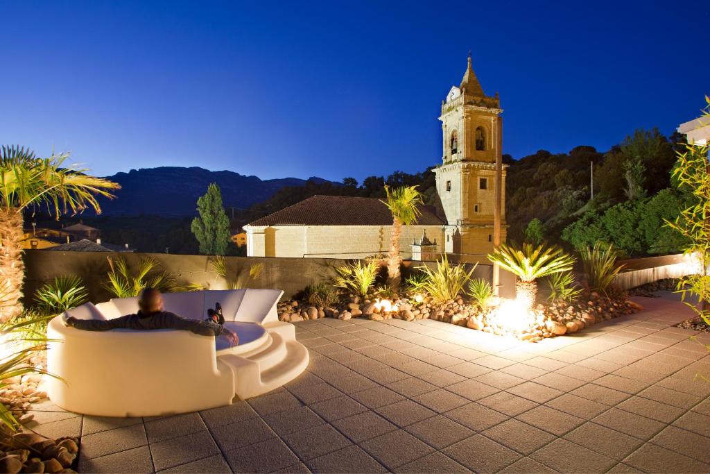 Hotel Viura: varanda iluminada com vista para igreja, sofá externo e paisagem noturna encantadora