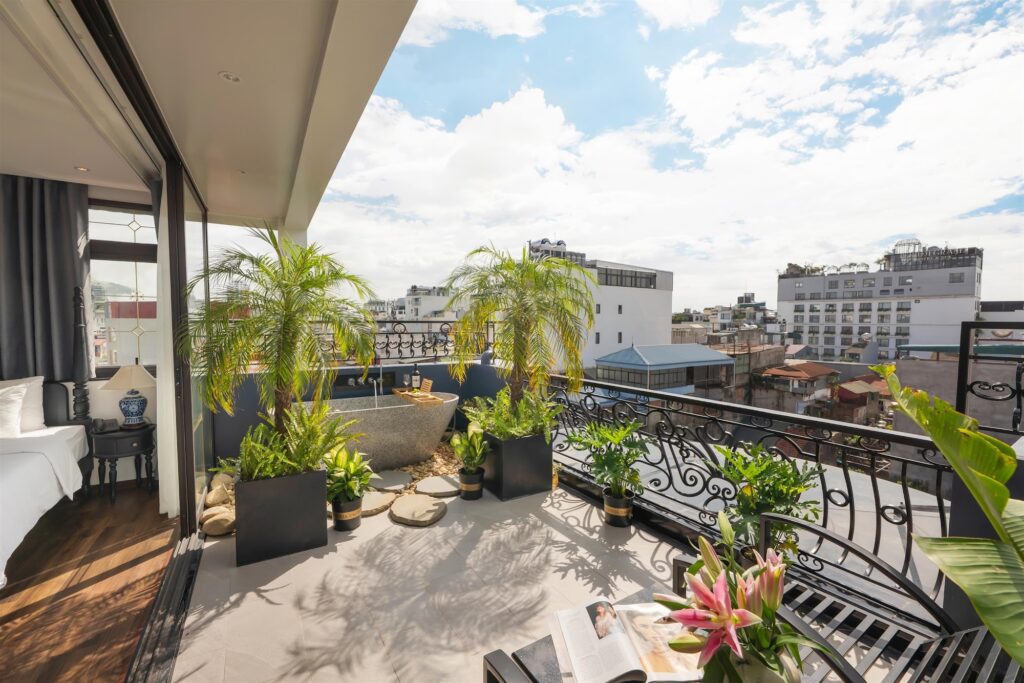 Banheira de pedra em varanda privativa com vista urbana no Le Chateau Hotel, um dos melhores hoteis em hanoi para relaxar.