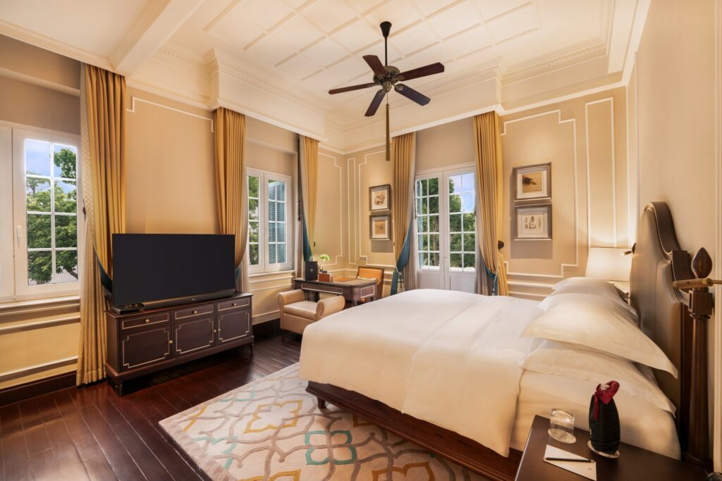 Quarto de design colonial no Sofitel Legend Metropole, um dos melhores hoteis em hanoi, com boiseries e móveis clássicos de madeira.
