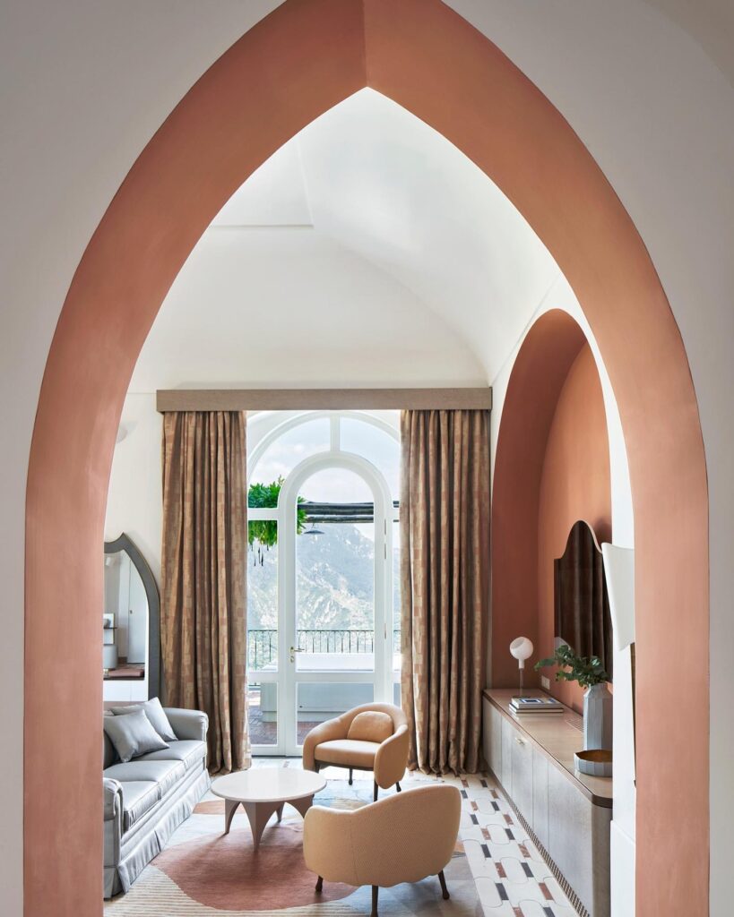 Sala luxuosa com arcos ogivais cor terracota e vista para as montanhas, ideal para quem busca onde ficar em amalfi com design sofisticado.