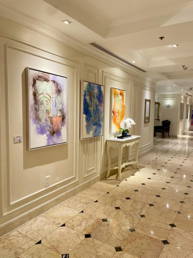 Galeria de arte em corredor luxuoso com boiseries e piso de mármore no Sofitel Legend Metropole, referência em hoteis em hanoi.