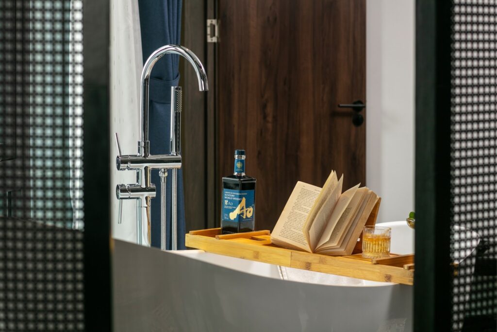 Detalhe de banheira de imersão com bandeja de madeira e whisky no Le Chateau Hotel, referência de luxo entre hoteis em hanoi.