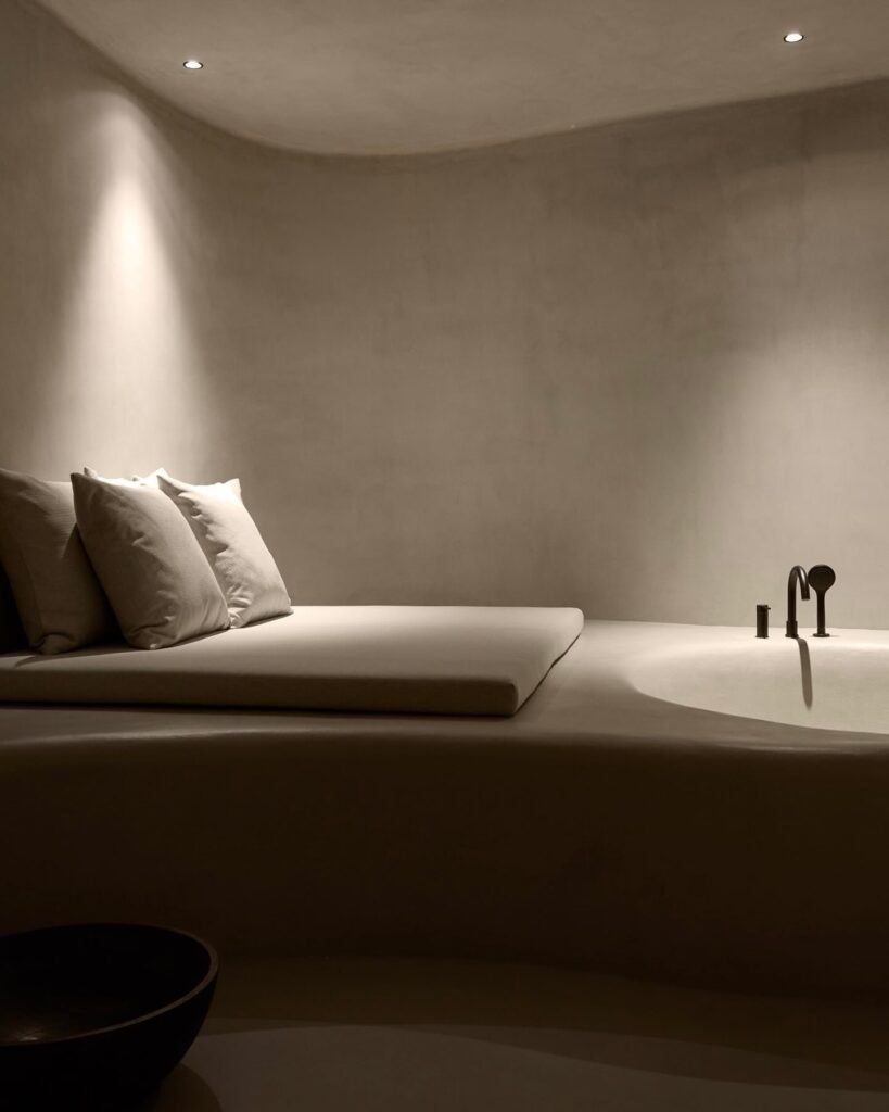 Spa de hotel italiano com paisagem alpina, banheira embutida e plataforma em estuque contínuo bege, design minimalista radical.