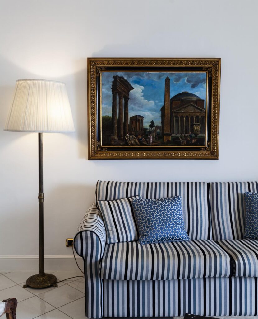 Detalhe de sofá listrado azul e branco com quadro clássico ao fundo em suíte de design, opção de onde ficar em amalfi.