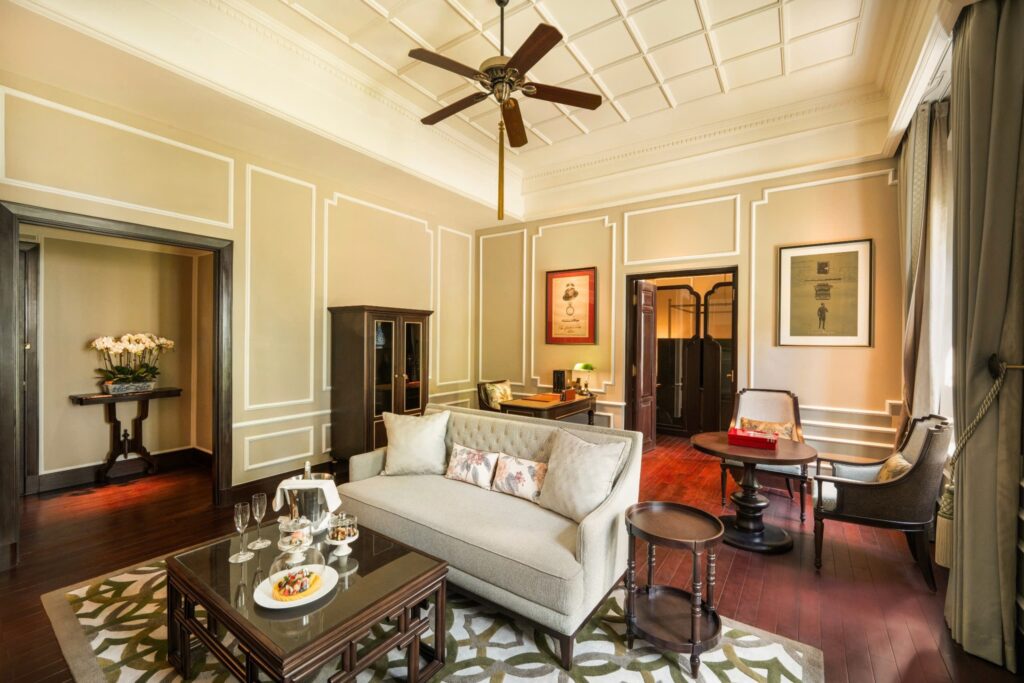 Sala de estar clássica com teto ornamentado e móveis franceses no Sofitel Legend Metropole, exemplo de sofisticação em hoteis em hanoi.