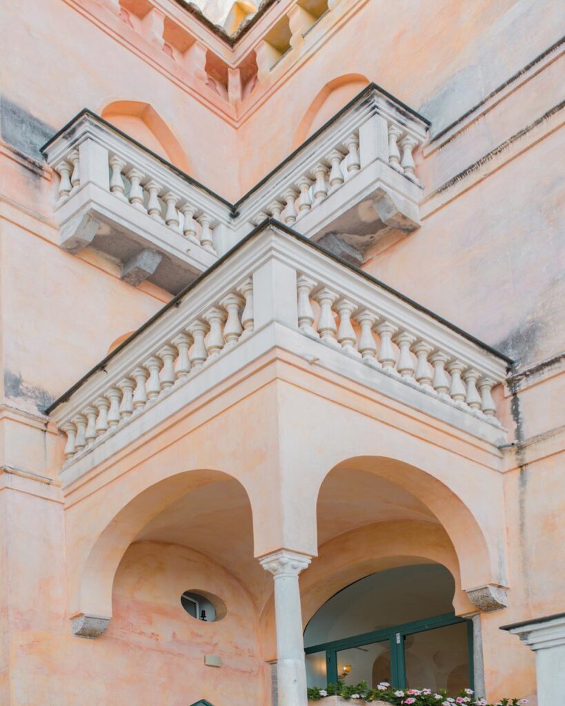 Arquitetura mediterrânea com balcões clássicos em tons de pêssego, detalhe charmoso de onde ficar em amalfi.