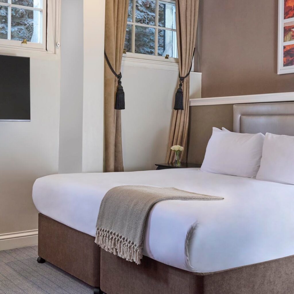 Cama confortável com cabeceira elegante em apart hotel em edimburgo.