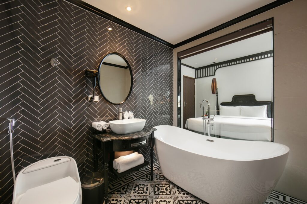 Banheiro com revestimento em espinha de peixe e banheira de design no Le Chateau Hotel, ícone de estilo entre hoteis em hanoi.