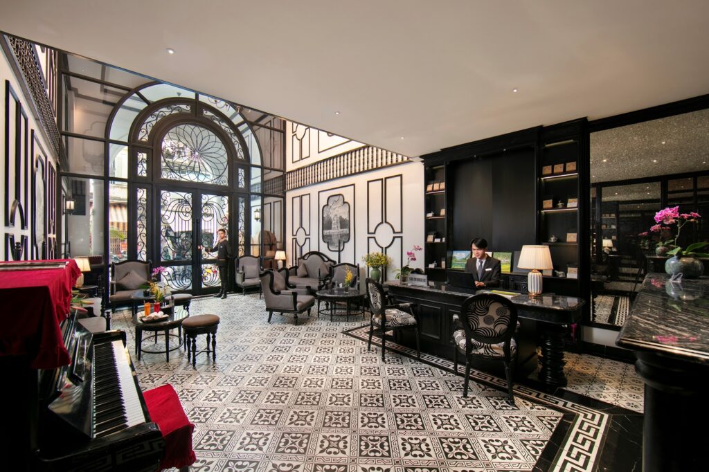 Lobby elegante com design colonial francês e piso decorado no Le Chateau Hotel, um dos principais hoteis em hanoi.