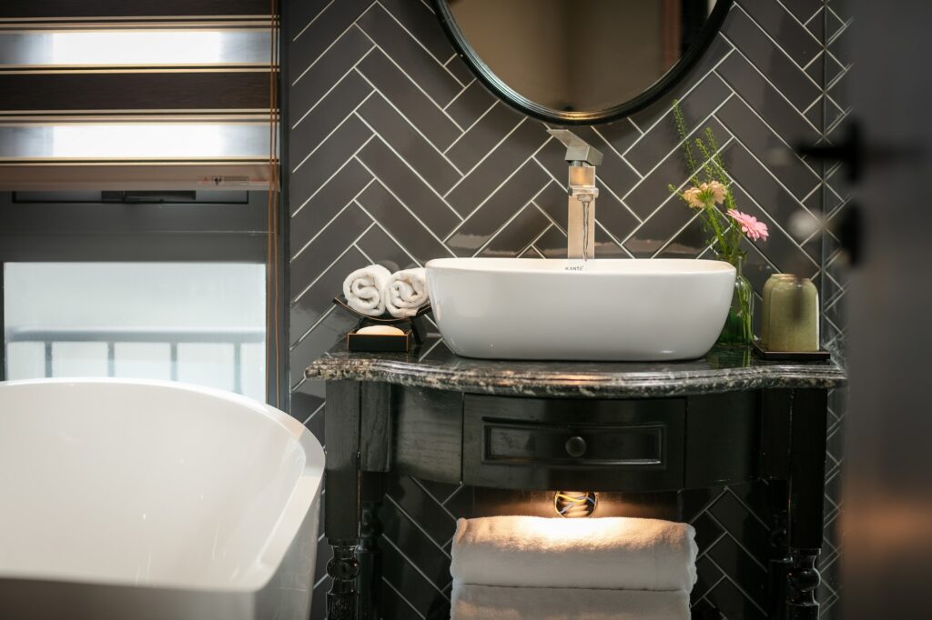 Detalhe de cuba de apoio e revestimento herringbone cinza em banheiro luxuoso de hoteis em hanoi como o Le Chateau Hotel.