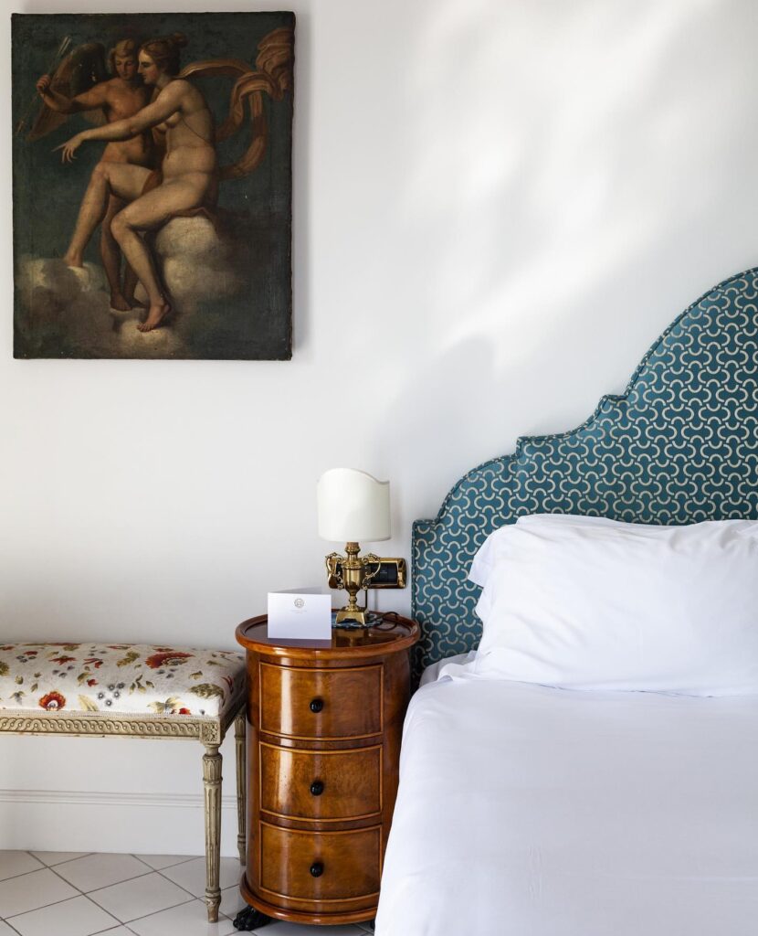 Cama de luxo com cabeceira azul e móveis clássicos de madeira, elegância em onde ficar em amalfi.