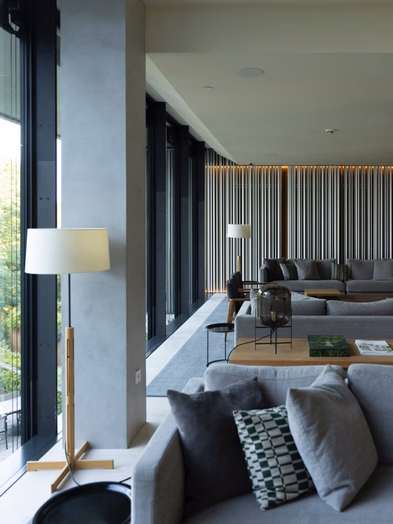 Lobby sofisticado com sofás cinzas e painel ripado de madeira no Arima Hotel & Spa San Sebastian.