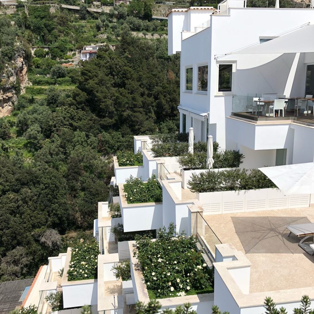 Fachada branca do hotel integrada à natureza costeira, opção premium de onde ficar em amalfi.