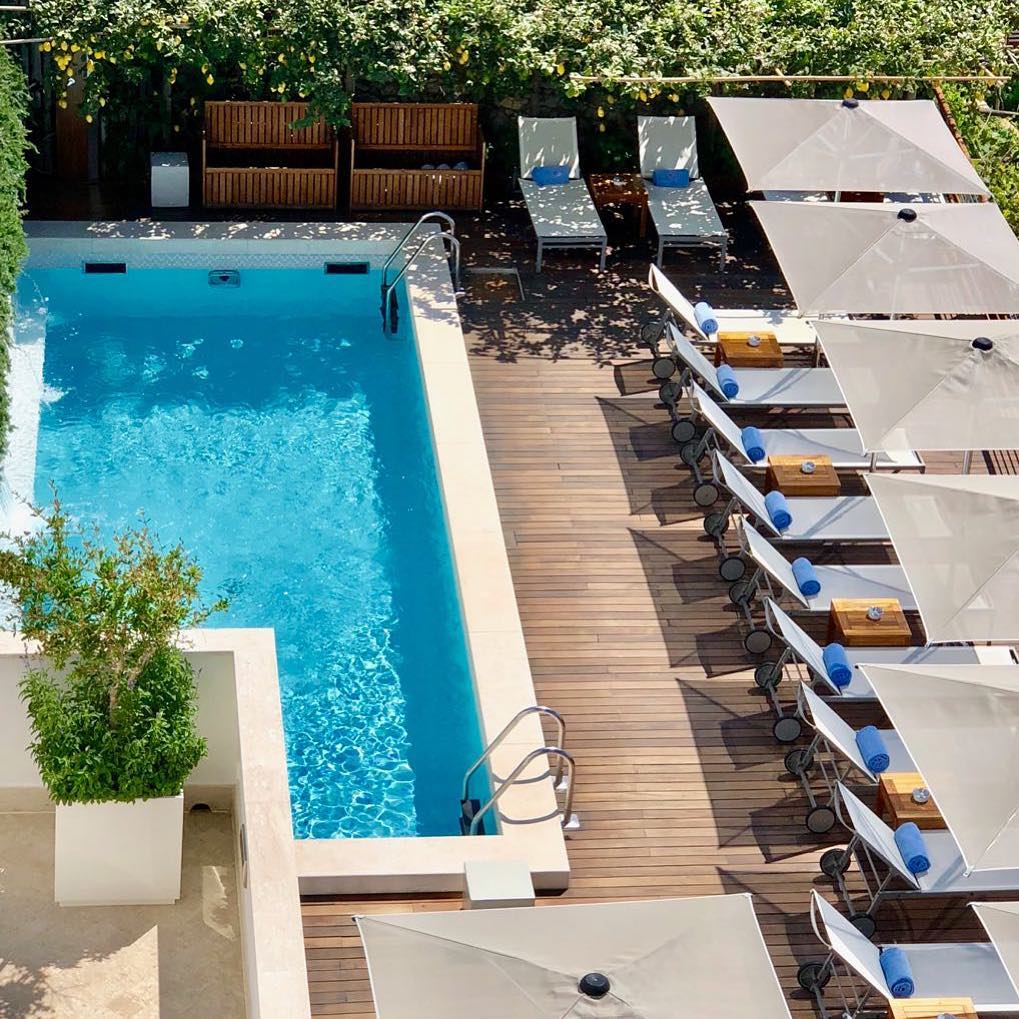 Piscina com deck de madeira e limoeiros ao redor, um refúgio de onde ficar em amalfi para relaxar.