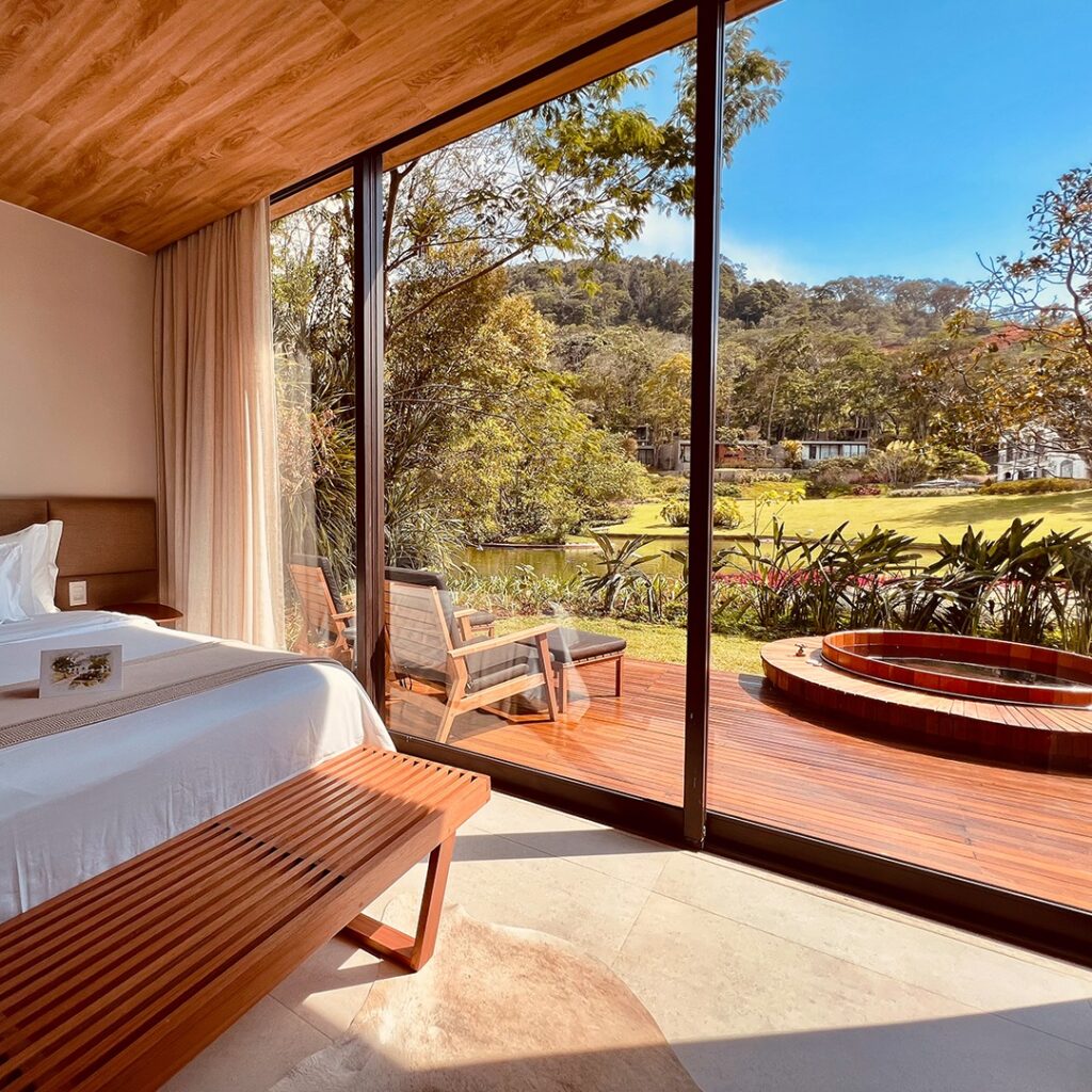 Interior de suíte iluminada com vista para jardins e lago, seu próximo refúgio para a páscoa.