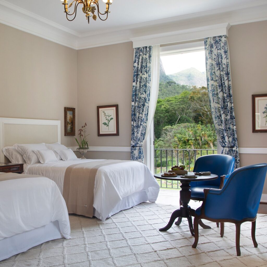 Quarto clássico com poltronas azuis e vista para as montanhas, seu refúgio para a páscoa na serra.