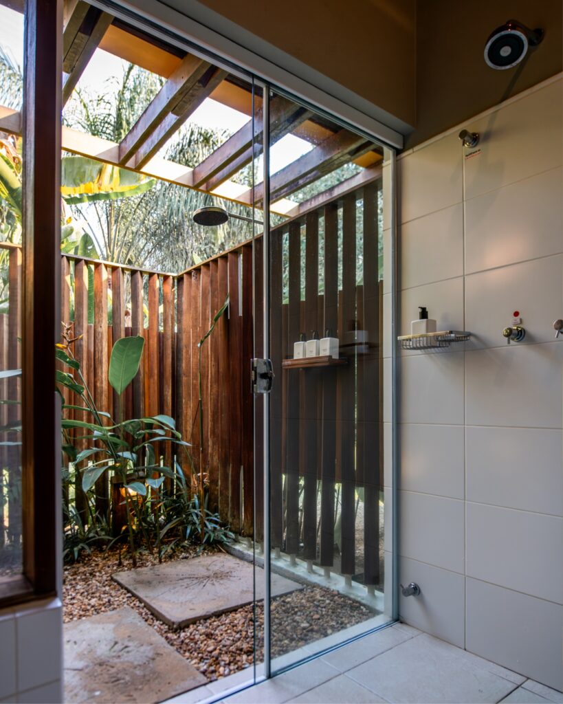 Banheiro externo com ducha e plantas, detalhe de sofisticação em um refúgio para a páscoa sustentável.