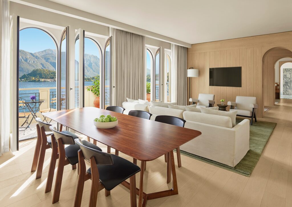 Suite ampla com mesa de jantar em nogueira e janelas arqueadas com vista para o lago no The Lake Como EDITION, hotéis no lago di Como.